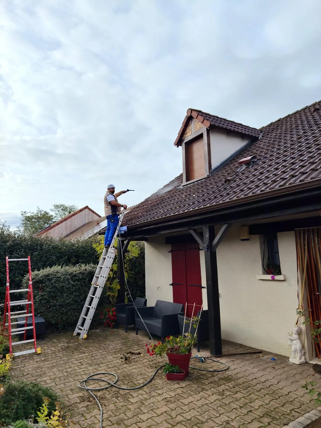 Professionnel et échelle installés au niveau de la toiture pour une intervention.